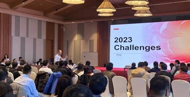 演讲者在会议室向台下观众展示主题为“2023 Challenges”的幻灯片。
